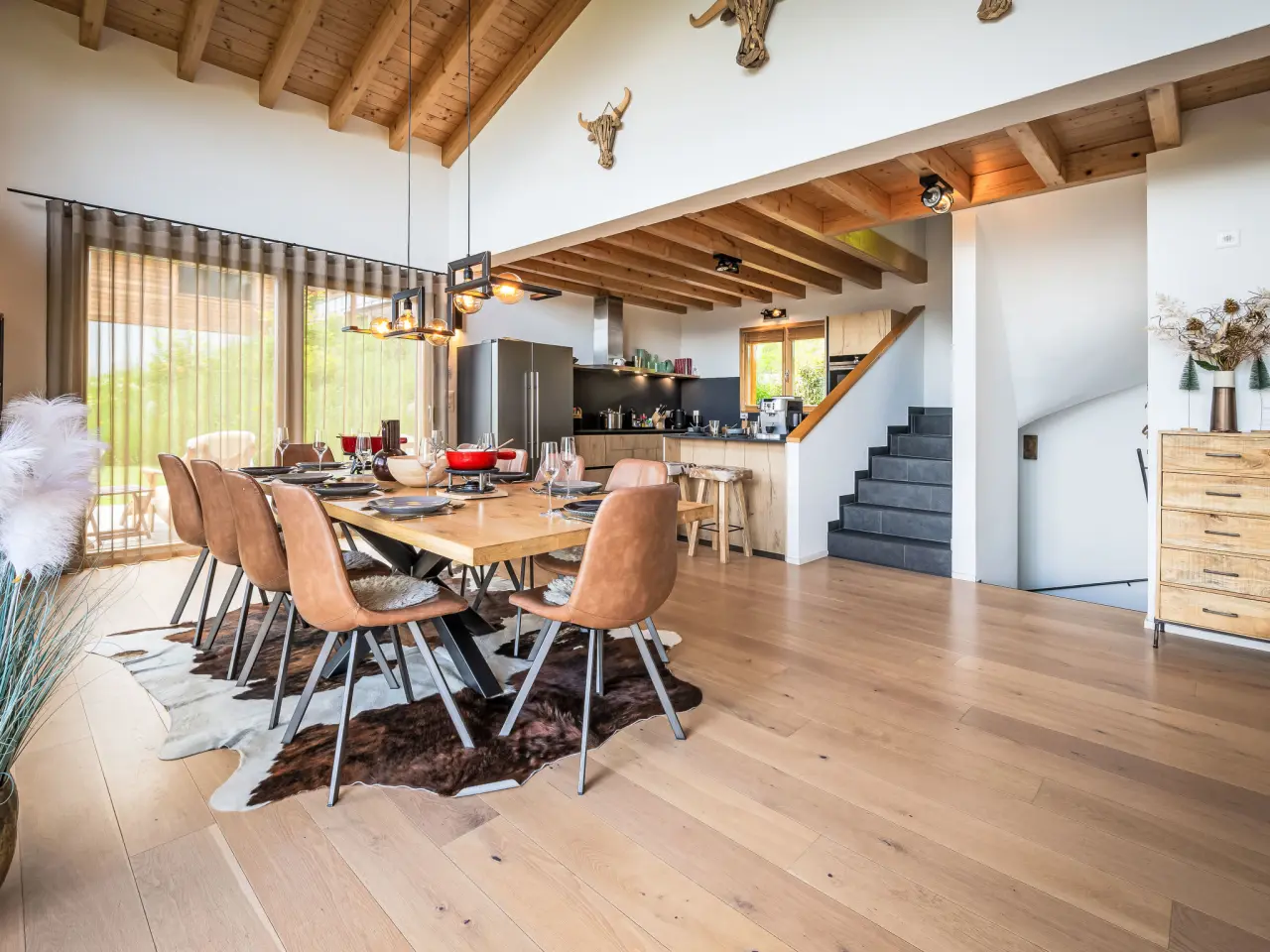 Woonkamer met eettafel voor tien en doorkijk naar de bergen